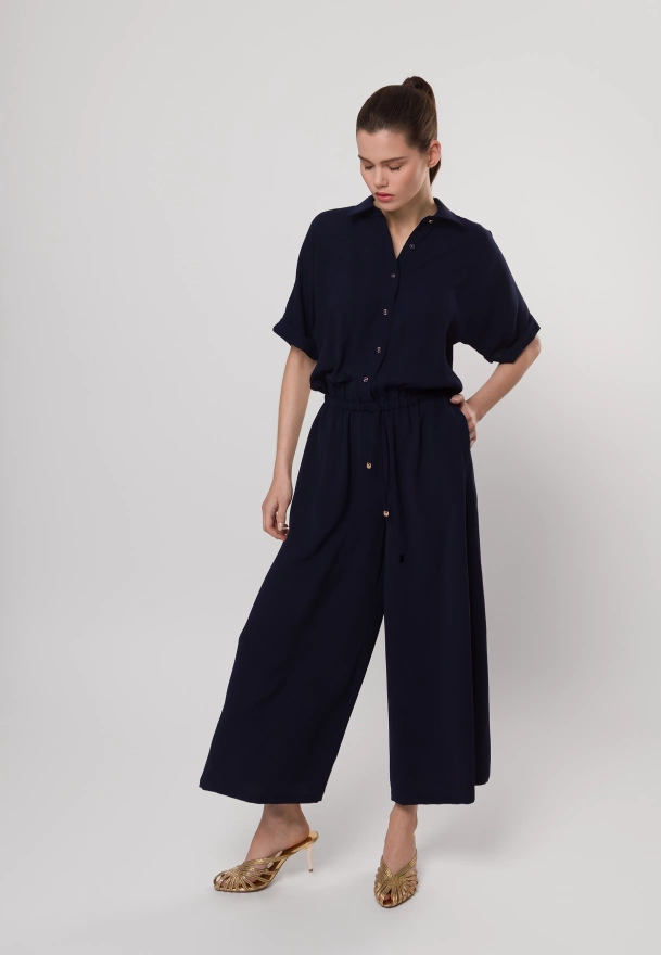Granatowy kombinezon zapinany do pasa z szerokimi nogawkami