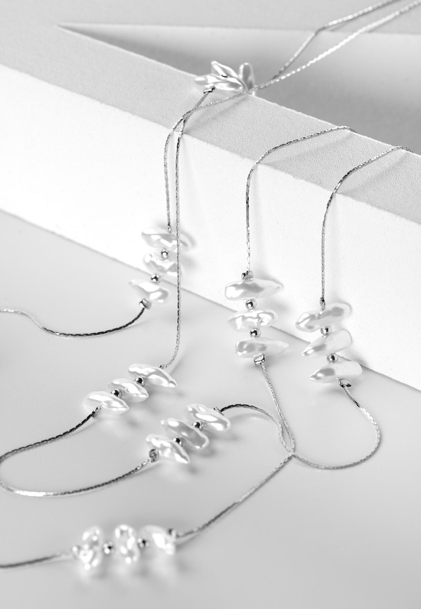 Komplet łańcuszków w kolorze srebrnym zdobiony perłowymi kamykami